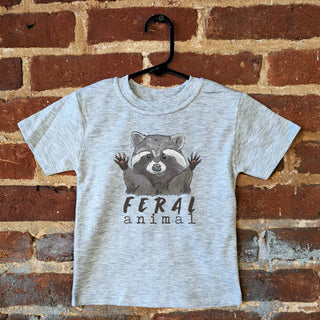 Gray t-shirt with raccoon graphic and 'Feral animal' text on a brick wall background