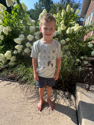 Child standing next to a bush with white flowers on a sunny day at JSQ Mercantile
