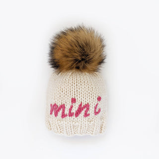 Mini Embroidered Toddler Hat with Brown Pom Pom – Hand-knit baby hat with “Mini” in cerise pink yarn. Sustainable and gift-ready. Available at JSQ Mercantile in La Grange, IL.
