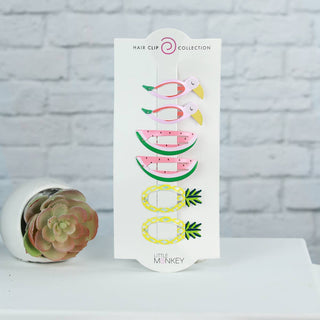Hair clip collection packaging with succulent plant on a white surface and gray brick wall background