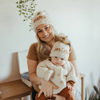 Mini Me Peanut Beanie Hat – Neutral hand-knit baby hat with “Mini” embroidery and brown pom pom. Eco-friendly and gift-ready. Available at JSQ Mercantile in La Grange, IL.

