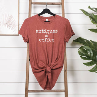 Red t-shirt with 'antiques & coffee' text on a wooden ladder against a white wall.