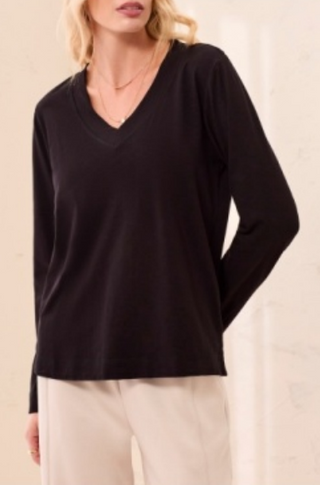 A woman wearing a black long sleeve V-neck top with a relaxed fit.