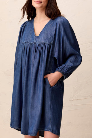 Puff sleeve dress in medium wash with a V-neckline and pockets, made of denim-like fabric.